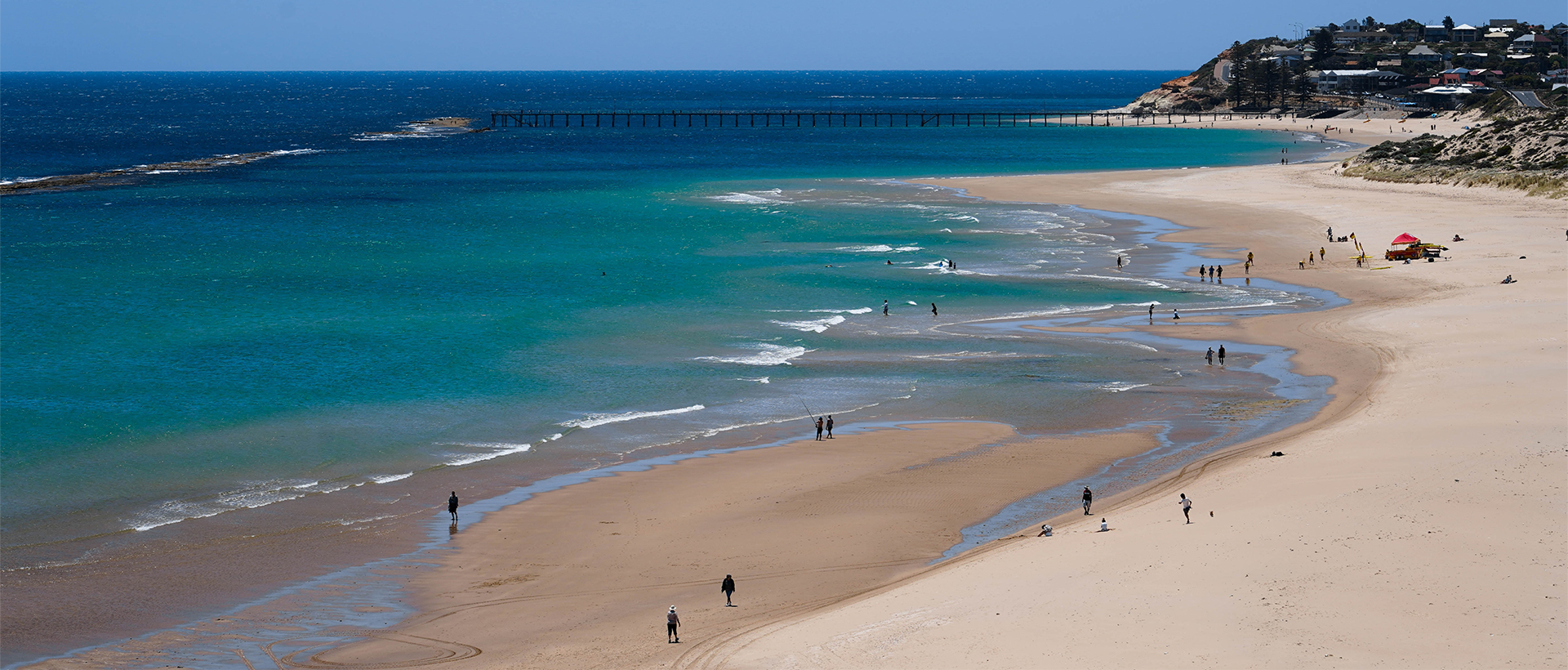 A beach with people walking on it and the ocean in the background.